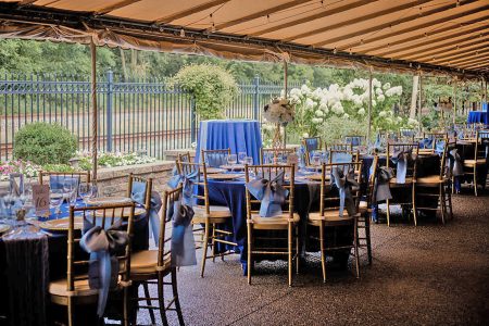 Gold chiavari chairs are set on the covered Trackside Courtyard surrounded by gardens