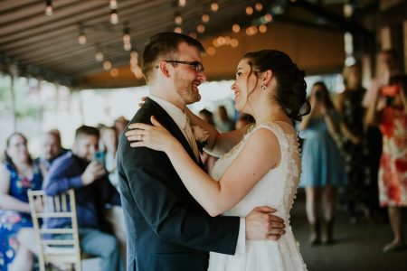 Bride and groom dance under vintage bulb lighting on the Trackside Courtyard.